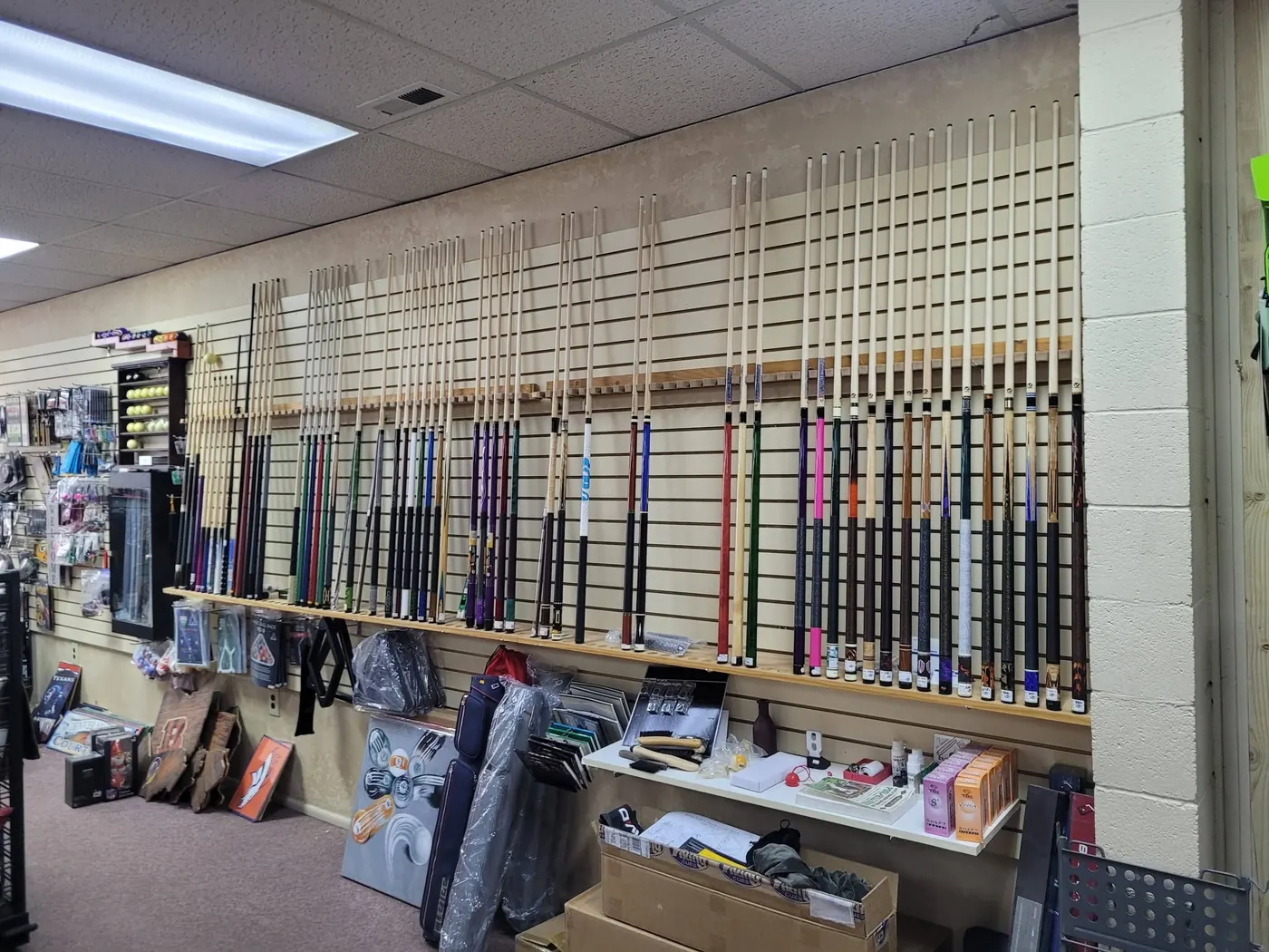 Wall of pool cues in racks at the LEMCO store