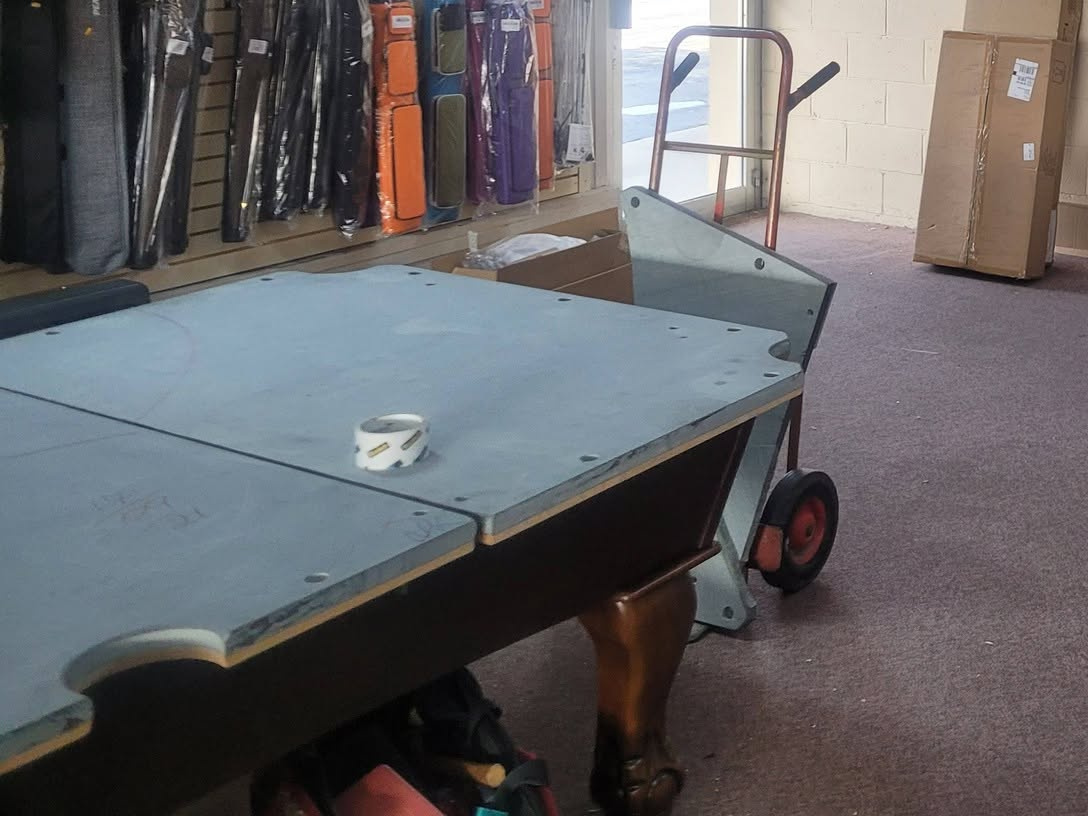 Slate pool table top next to a hand truck, ready for setup or moving